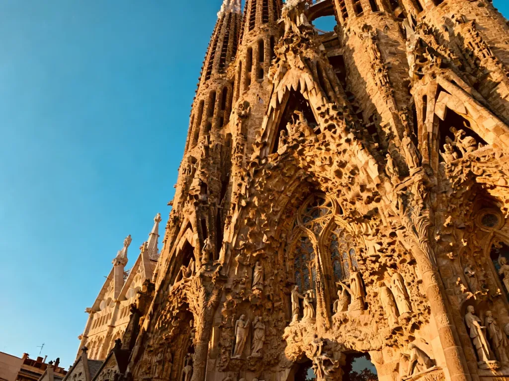 Szczegółowe rzeźby na fasadzie bazyliki Sagrada Família oświetlone ciepłym światłem zachodzącego słońca.
