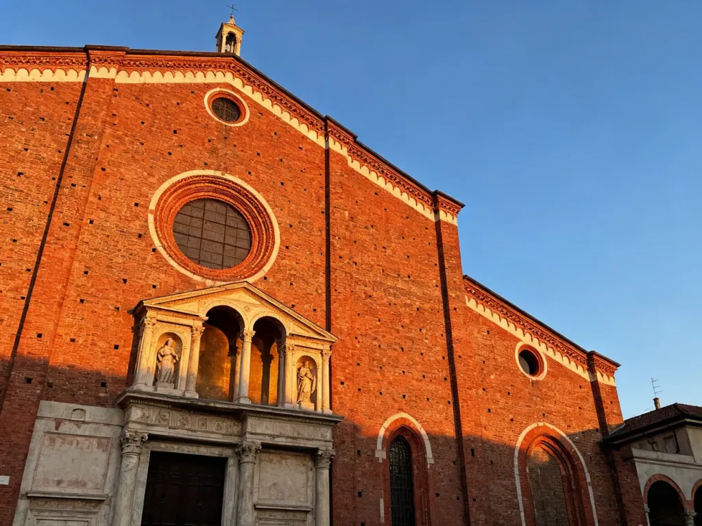Fasada kościoła Santa Maria delle Grazie w Mediolanie w ciepłym świetle zachodzącego słońca.