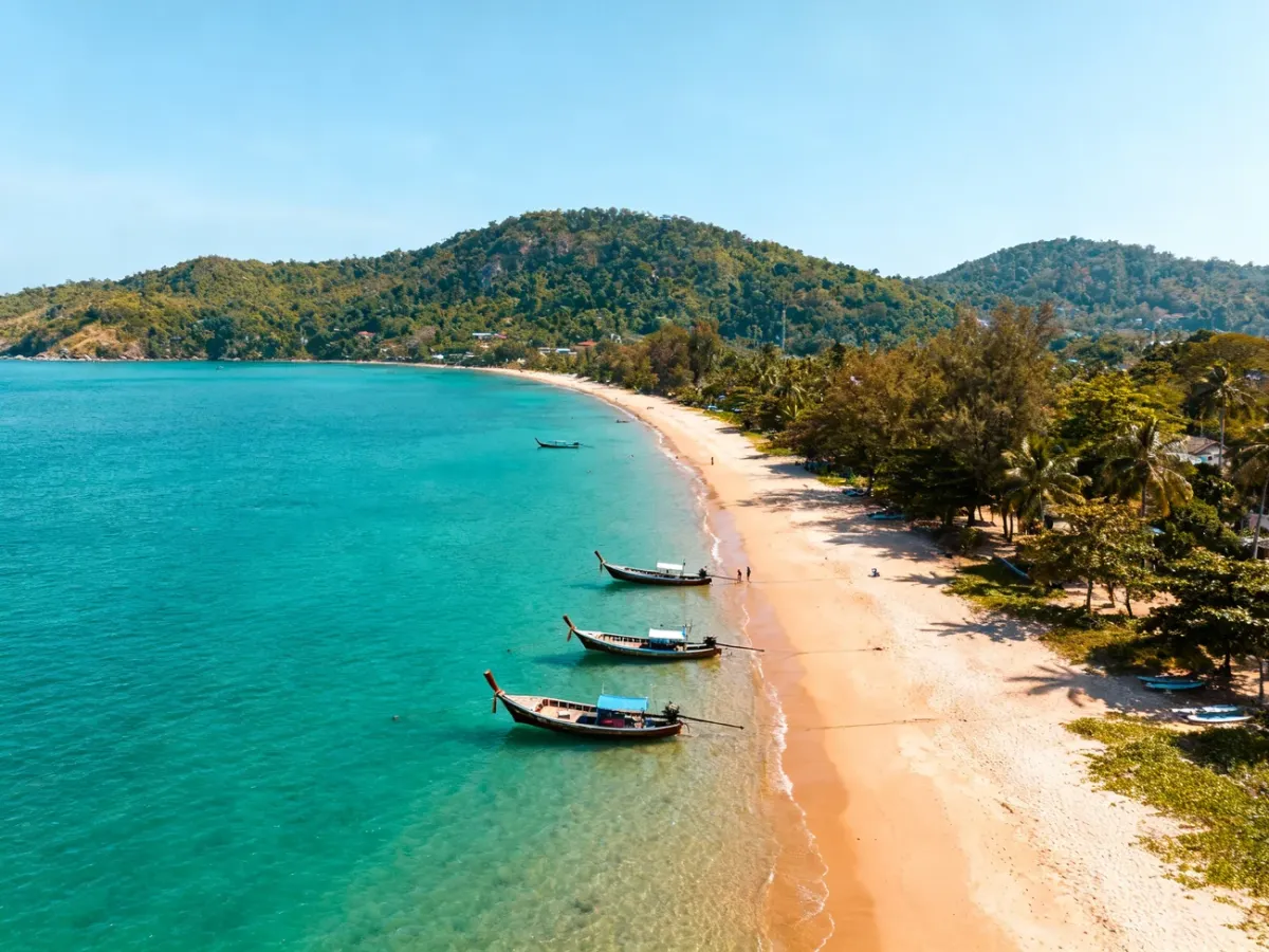 Tropikalne wybrzeże Phuket ze spokojnym morzem i łodziami longtail