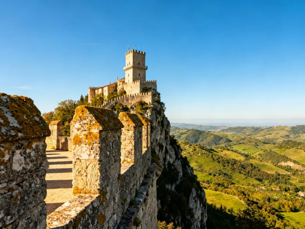 Widok na zabytkową wieżę Guaita na skalistym klifie w San Marino w promieniach słońca.